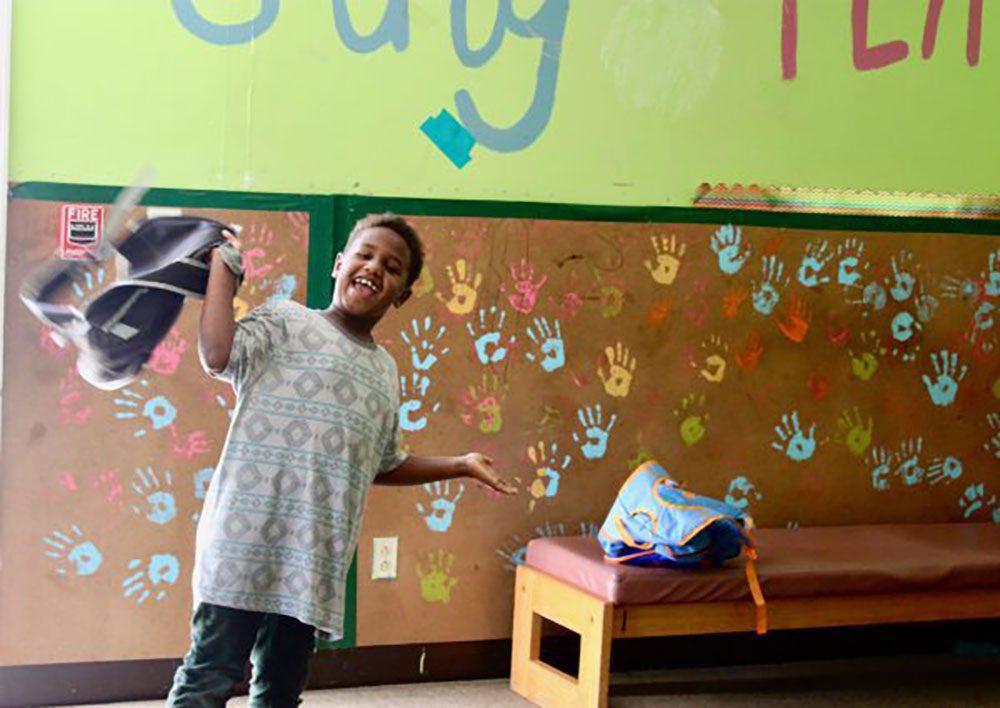 A child smiles in front of classroom art