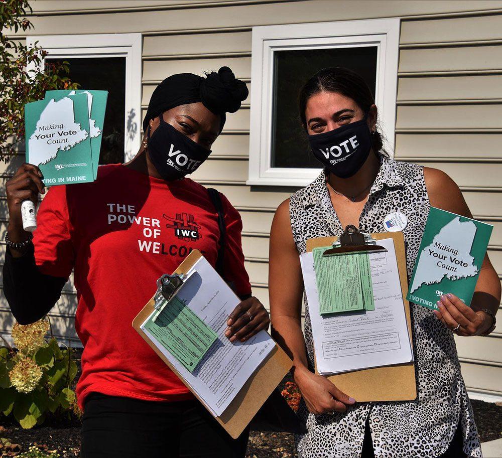 Two women wear masks while walking house to house holding Making your vote count flyers