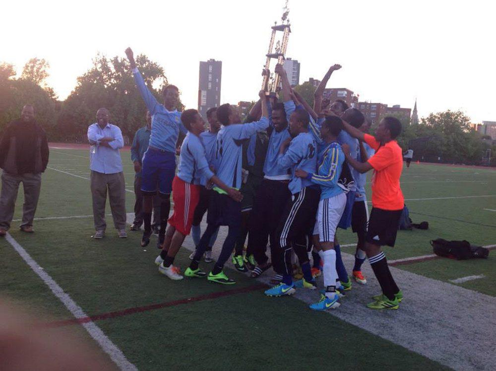 Young immigrant men celebrate with their soccer trophy