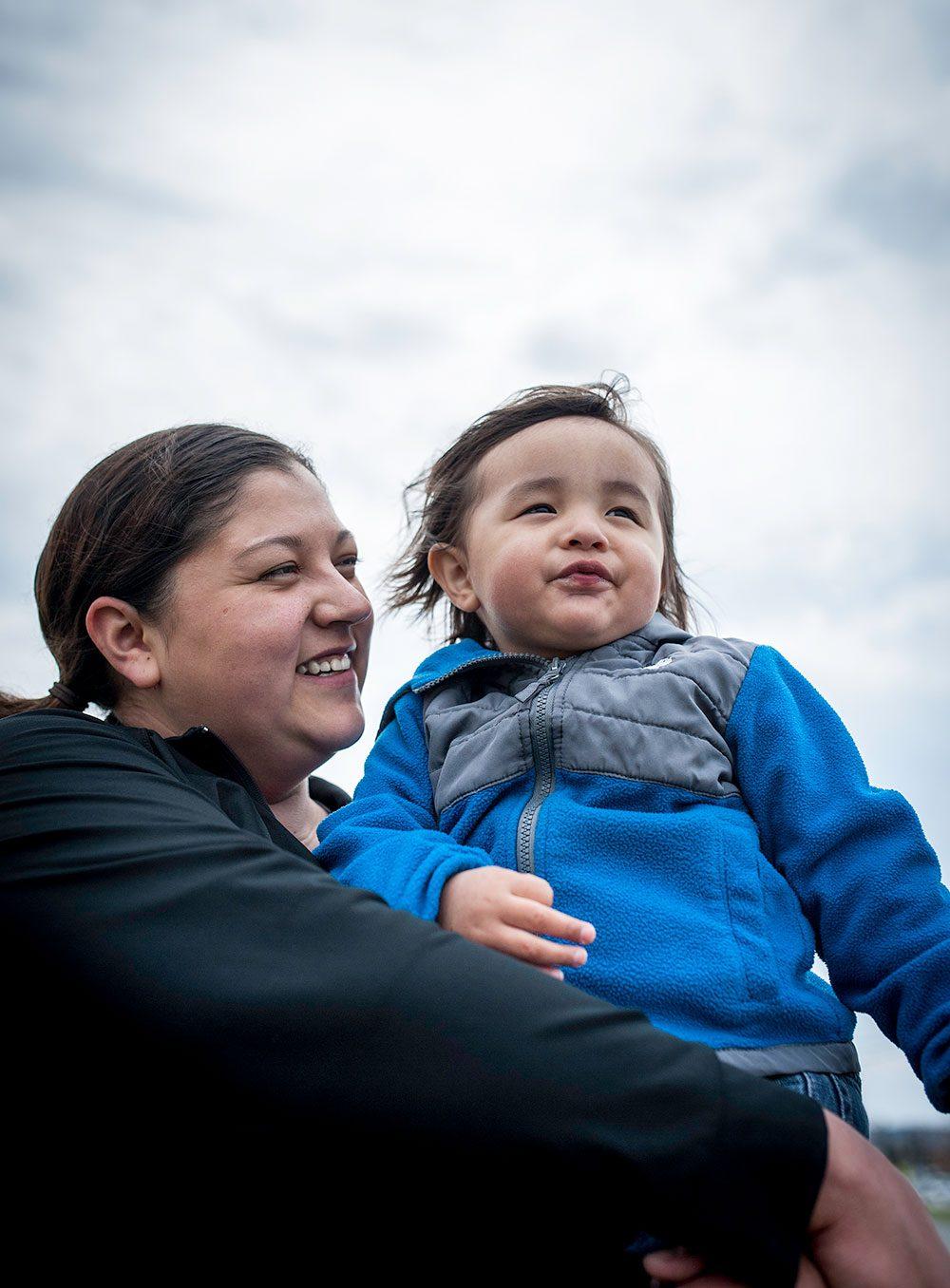 A Maine Wabanaki woman holds her child in her arms and smiles