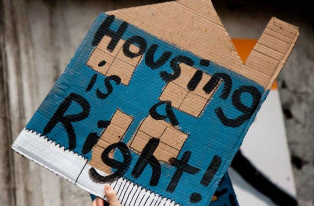 A cardboard house cut-out with the words, housing is a right!