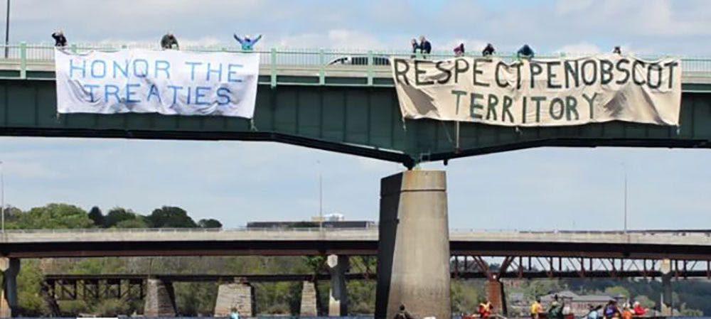 Protest signs hang on a highway cross over bridge